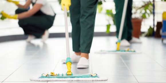 A team of professional cleaners work on showroom cleaning services for a car dealership.