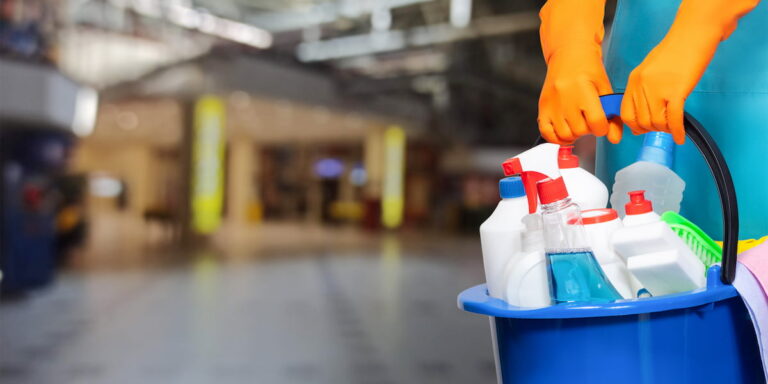 Professional cleaner with blue bucket full of cleaning supplies performing common area cleaning in condominium lobby with orange gloves