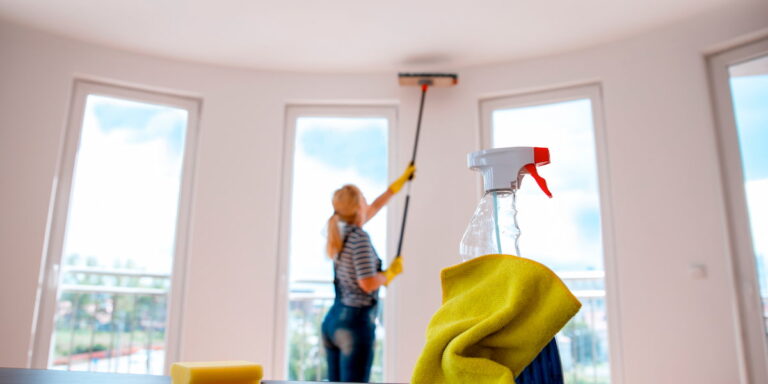 Person cleaning a condo ceiling with spray bottle and sponge in foreground, illustrating professional condo building cleaning process.