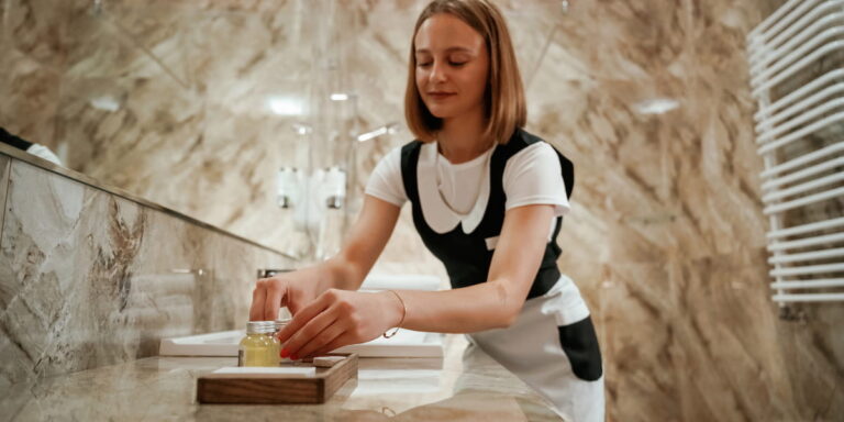 Female porter arranging toiletries in a luxury restroom as part of day porter services to maintain cleanliness and guest satisfaction