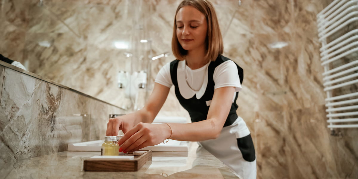 Female porter arranging toiletries in a luxury restroom as part of day porter services to maintain cleanliness and guest satisfaction