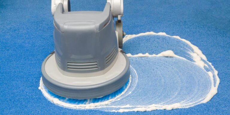 Machine scrubbing blue carpet with foam during encapsulation carpet cleaning to show how the low moisture process lifts soil from the surface.