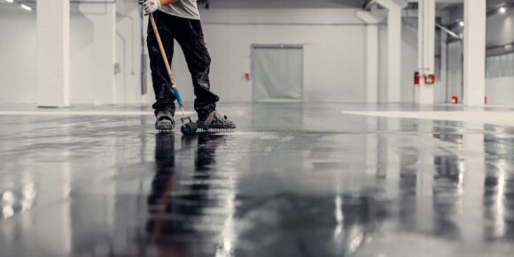 Worker cleaning a commercial rubber floor surface showing how to clean rubber flooring using professional equipment in an industrial space