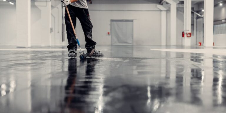 Worker cleaning a commercial rubber floor surface showing how to clean rubber flooring using professional equipment in an industrial space