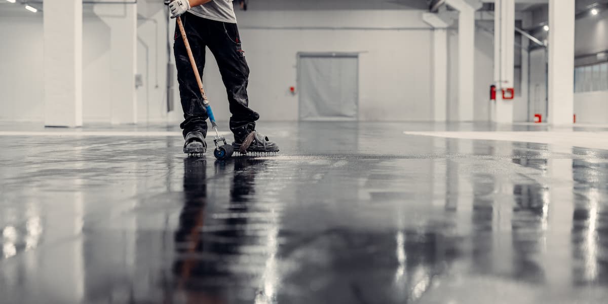 Worker cleaning a commercial rubber floor surface showing how to clean rubber flooring using professional equipment in an industrial space